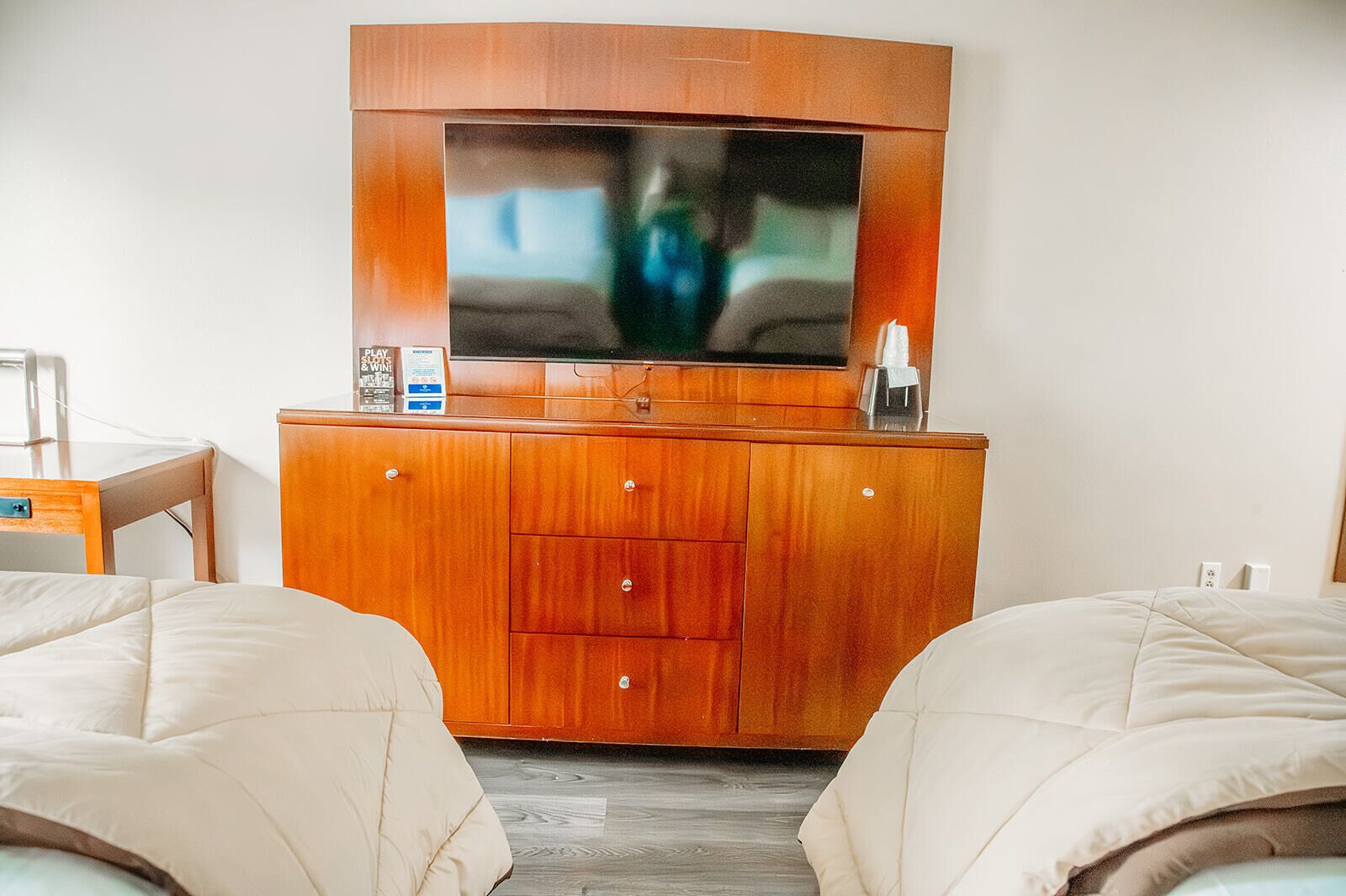 A hotel room with a wooden cabinet, a television, and two beds.