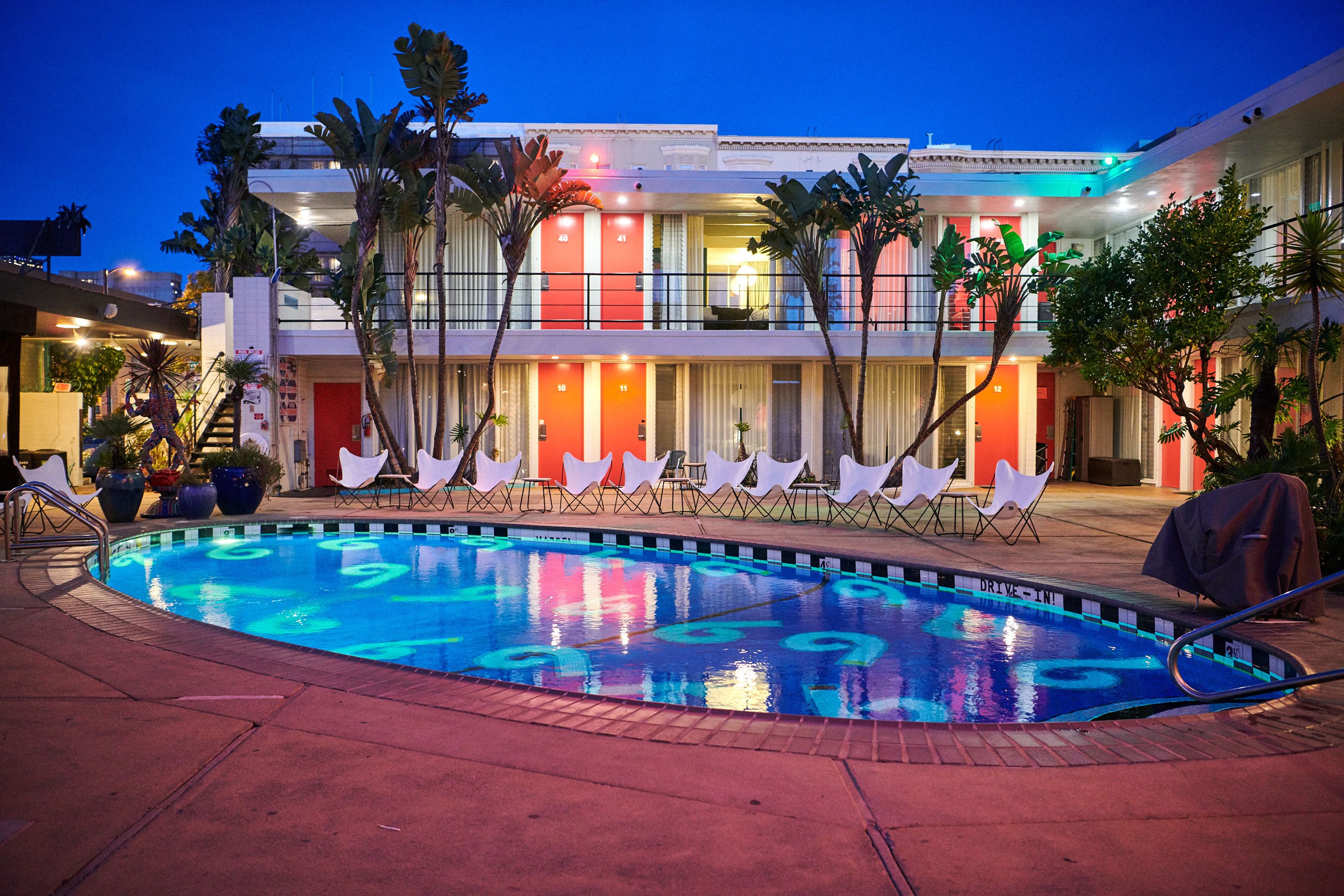 A hotel with a swimming pool, multiple balconies, and a drive-in entrance.