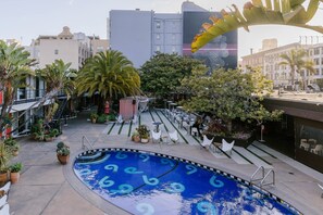 A rooftop pool with a blue design, surrounded by potted plants and outdoor seating. - The Phoenix Hotel (San Francisco)