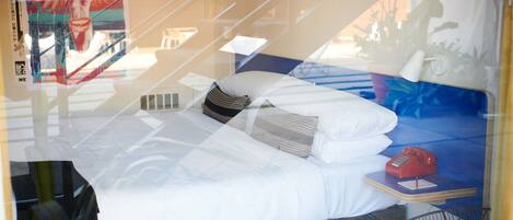 A hotel room with a bed, pillows, a telephone, and a window with a view of the outside.