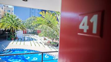 A pool area with a blue pool, palm trees, and a red wall with the number 41.