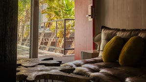 A leather sofa with two cushions, a wooden coffee table, and a view of a balcony with plants. - The Phoenix Hotel (San Francisco)