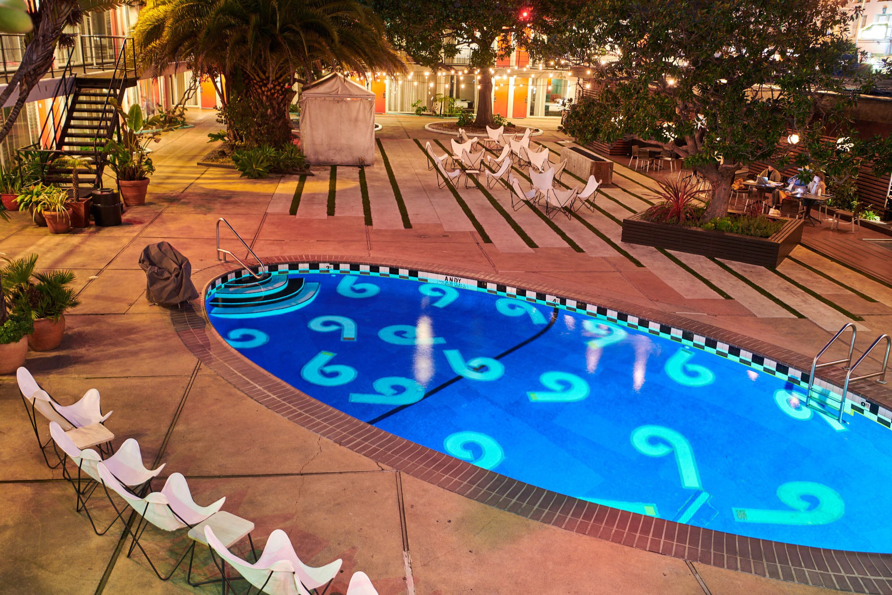 A swimming pool with a unique number pattern, surrounded by lounge chairs and a staircase.