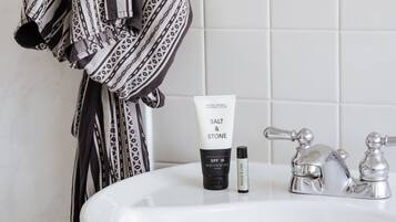 A bathroom sink with a bottle of sunscreen and a tube of lotion.
