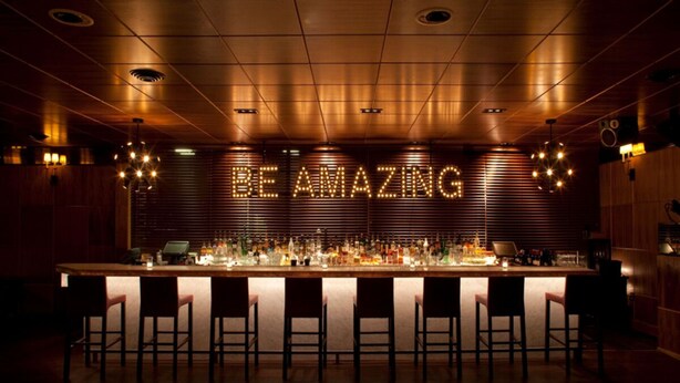 A bar area with a wooden ceiling, a bar counter, and multiple bar stools. - The Phoenix Hotel (San Francisco)