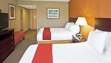 A hotel room with two beds, a TV, a desk, and a lamp.