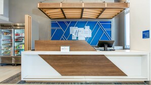 Un mostrador de recepción de diseño moderno, con una encimera de madera y un panel mural azul con motivos geométricos.