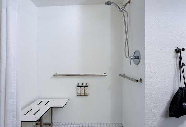 Ducha blanca con cabezal de ducha manual, barra de apoyo y perchero.