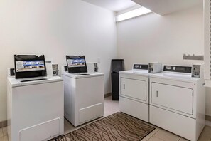 A laundry room with four washing machines, a dryer, and a wall-mounted control panel. - Comfort Inn Great Falls South (Great Falls)