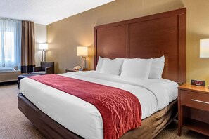 A hotel room with a large bed, a wooden headboard, a bedside table with a lamp, and a window with curtains. - Comfort Inn Great Falls South (Great Falls)