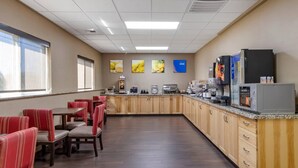 A hotel dining area with wooden cabinets, a coffee station, and red upholstered chairs. - Comfort Inn Great Falls South (Great Falls)