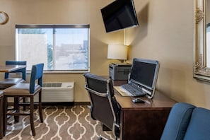 A hotel room with a desk, laptop, and TV. There is a window with a view, a chair, and a lamp. - Comfort Inn Great Falls South (Great Falls)