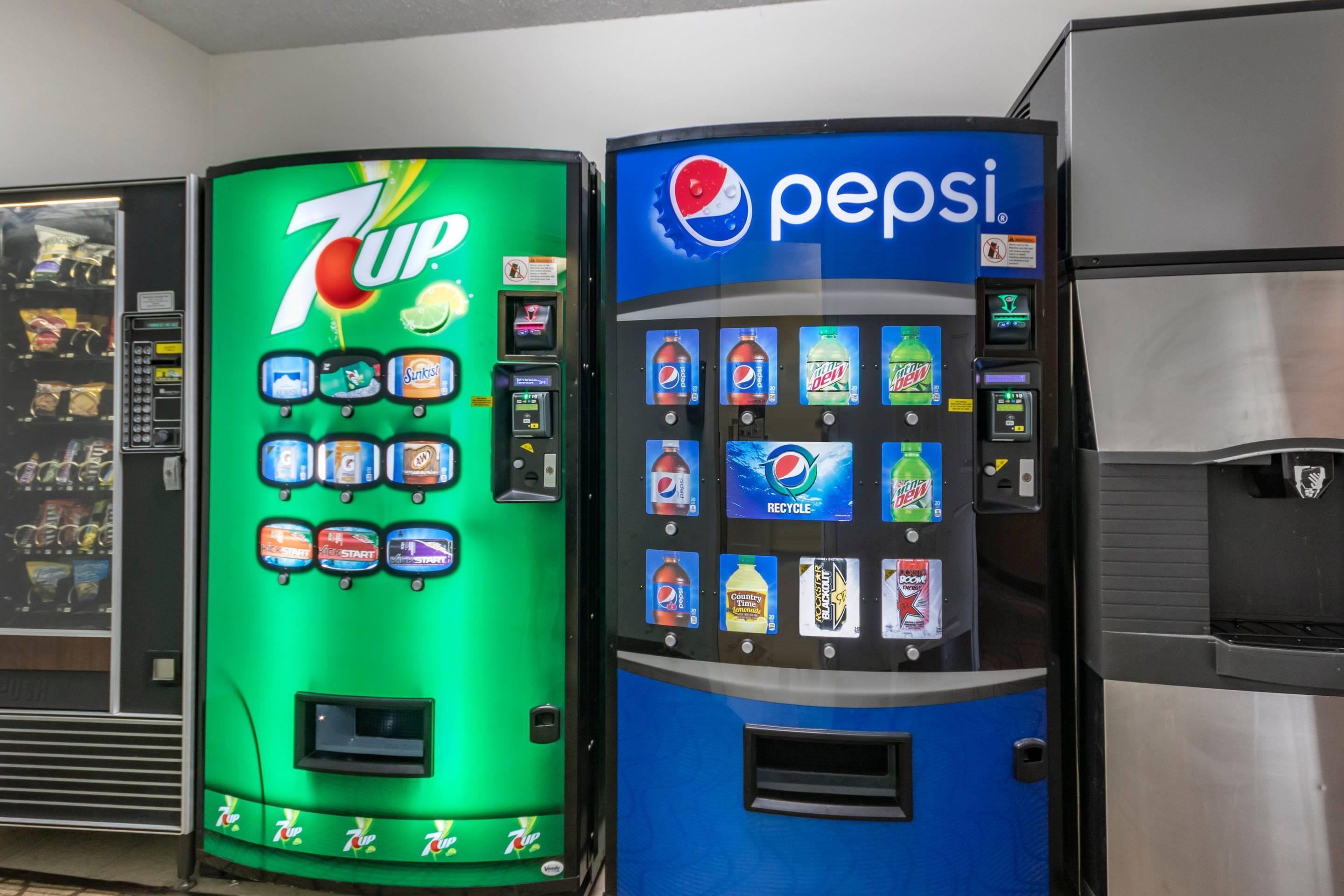 Due distributori automatici di bevande, uno per 7UP e uno per Pepsi, con diverse opzioni tra cui scegliere e il simbolo del riciclo.