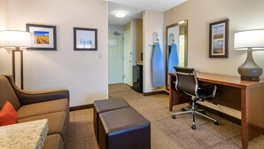 A hotel room with a sofa, a desk, a chair, a lamp, and framed pictures on the walls. - Comfort Inn Great Falls South (Great Falls)