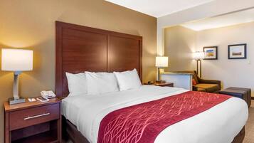 A hotel room with a large bed, two bedside tables, a nightstand, a desk, a chair, and two lamps.