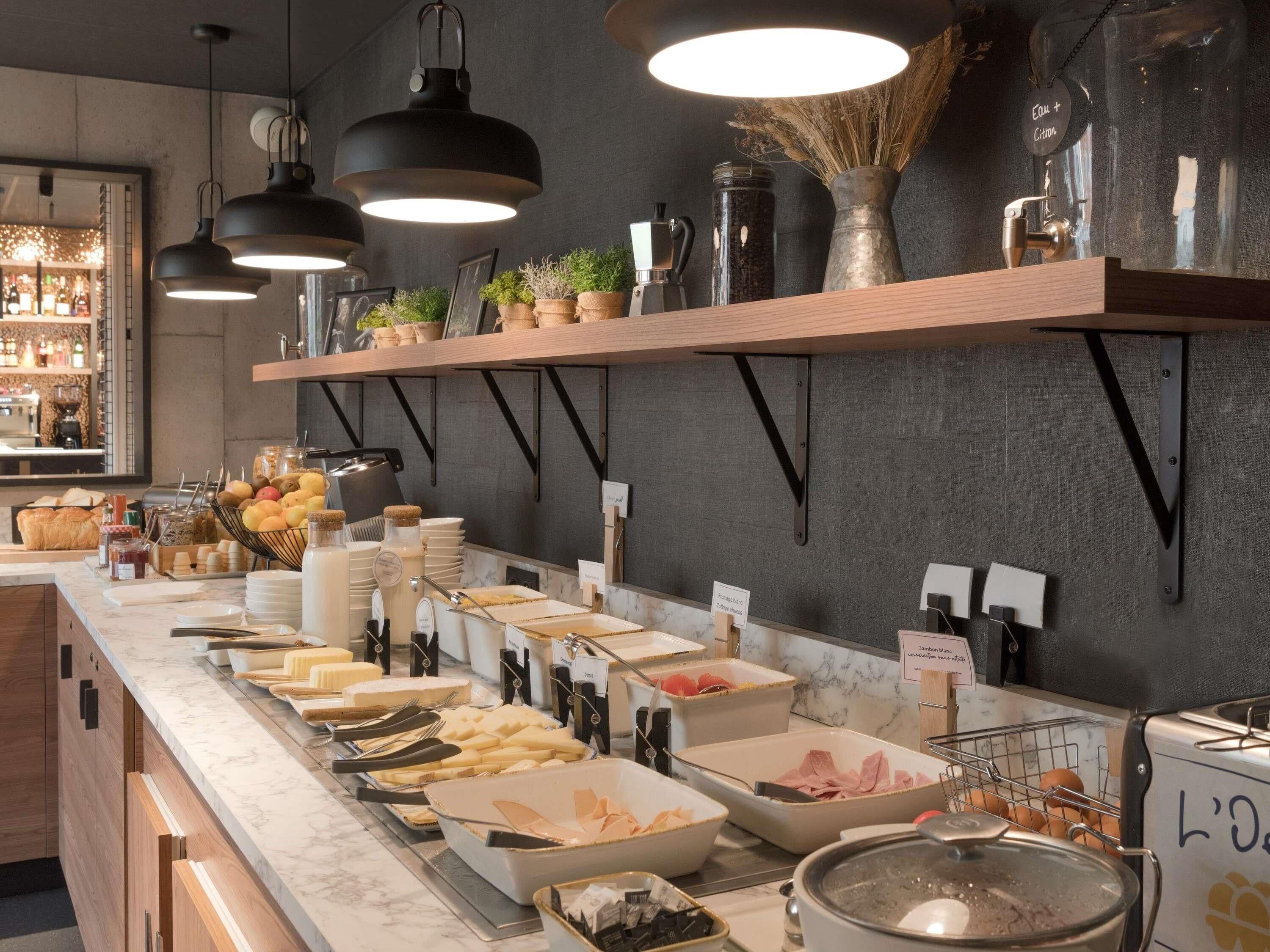 Montaje de bufé con diversas opciones de comida y utensilios, incluyendo cuencos con frutas, quesos y carnes, dispuestas sobre una encimera de mármol.