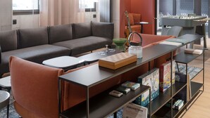 A modern lounge area with a sofa, coffee table, and bookshelves. - ibis Rueil-Malmaison Centre (Rueil-Malmaison)