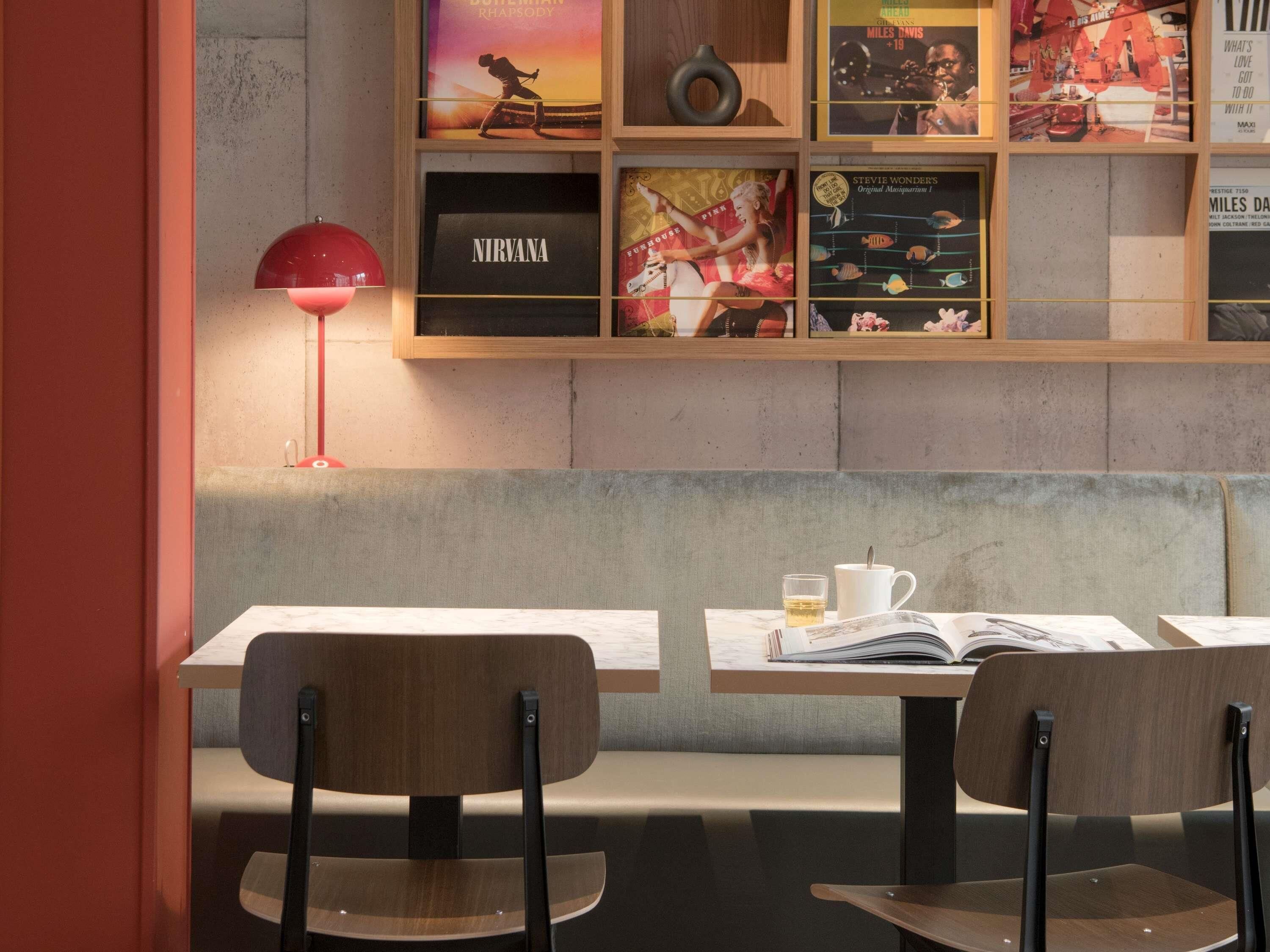 Ein modernes Interieur mit einem Holzbodenregal, auf dem verschiedene Poster und eine rote Lampe stehen.