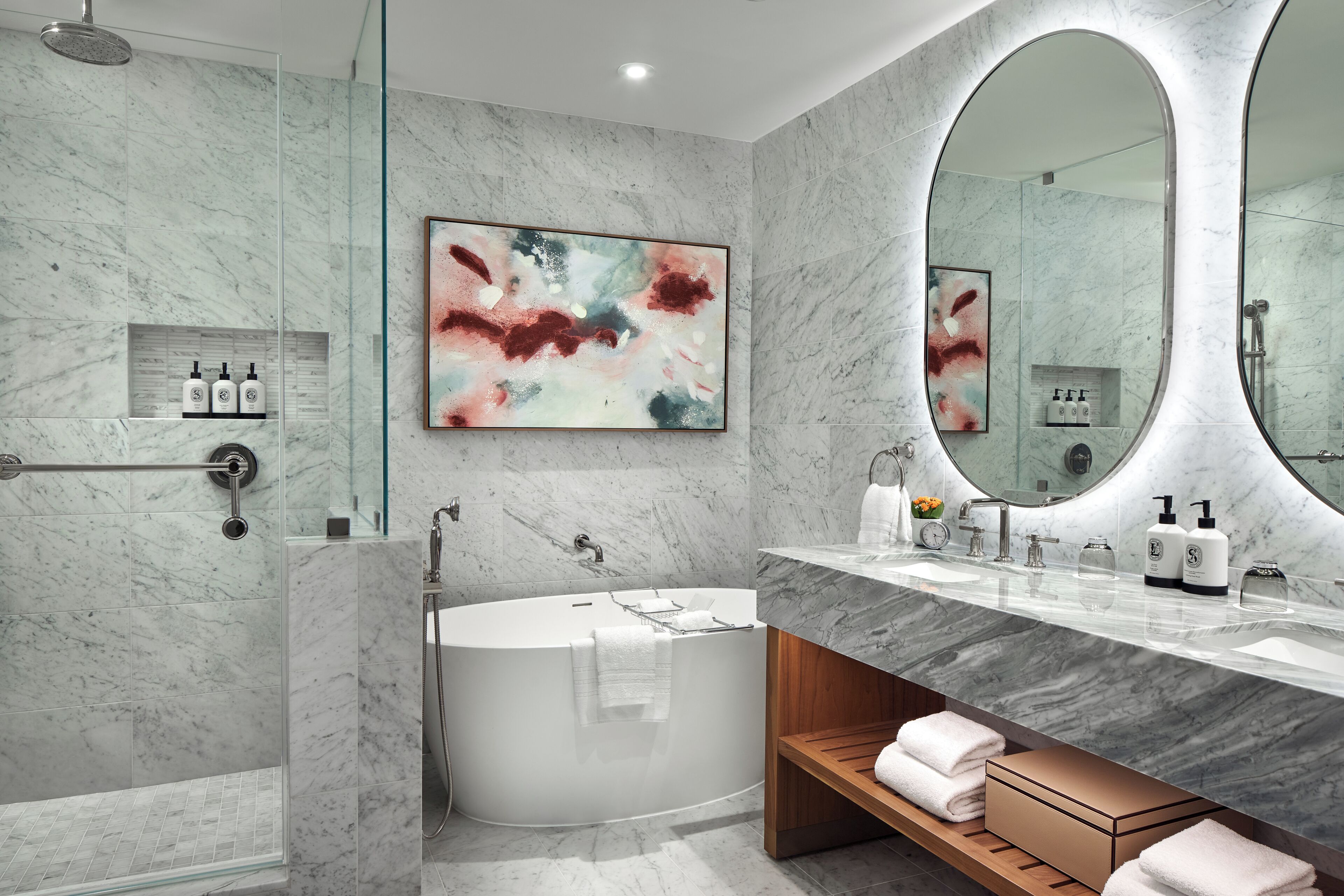 A modern bathroom with a freestanding bathtub, a large mirror, and a marble wall.