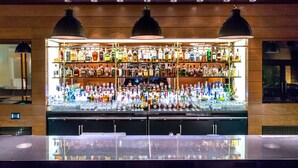 A bar area with multiple shelves of bottles and glasses, a bar counter, and overhead lighting. - Four Seasons Hotel Washington DC (Washington)