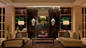 A lobby with a marble fireplace, two sofas, a coffee table, and decorative vases. - Four Seasons Hotel Washington DC (Washington)