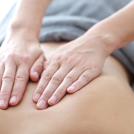 A close-up of hands performing a massage on a person's back.