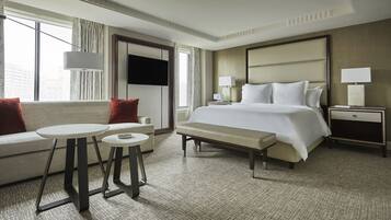 A hotel room with a bed, a sofa, a small table, and a nightstand.