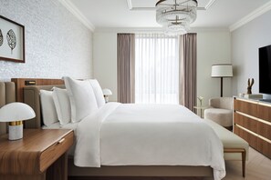 Relax in a serene space with a large bed, seating area, and flat-screen TV.