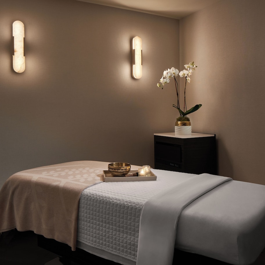 A neatly arranged bedroom with a bed, bedside table, and a vase with flowers.