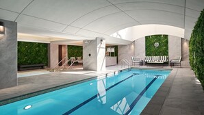 An indoor swimming pool with clear blue water, surrounded by lounge chairs and a green wall. - Four Seasons Hotel Washington DC (Washington)
