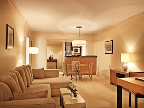 Habitación de hotel con sofá, una mesa de comedor, una zona de cocina y una lámpara.