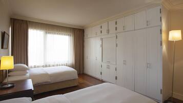 A hotel room with two beds, a wardrobe, and a lamp.