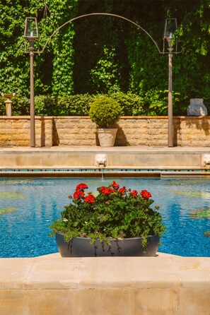 Ein Pool mit einem Blumenbeet aus roten Blüten, einer Steinsäule und einem Lampenpfosten.