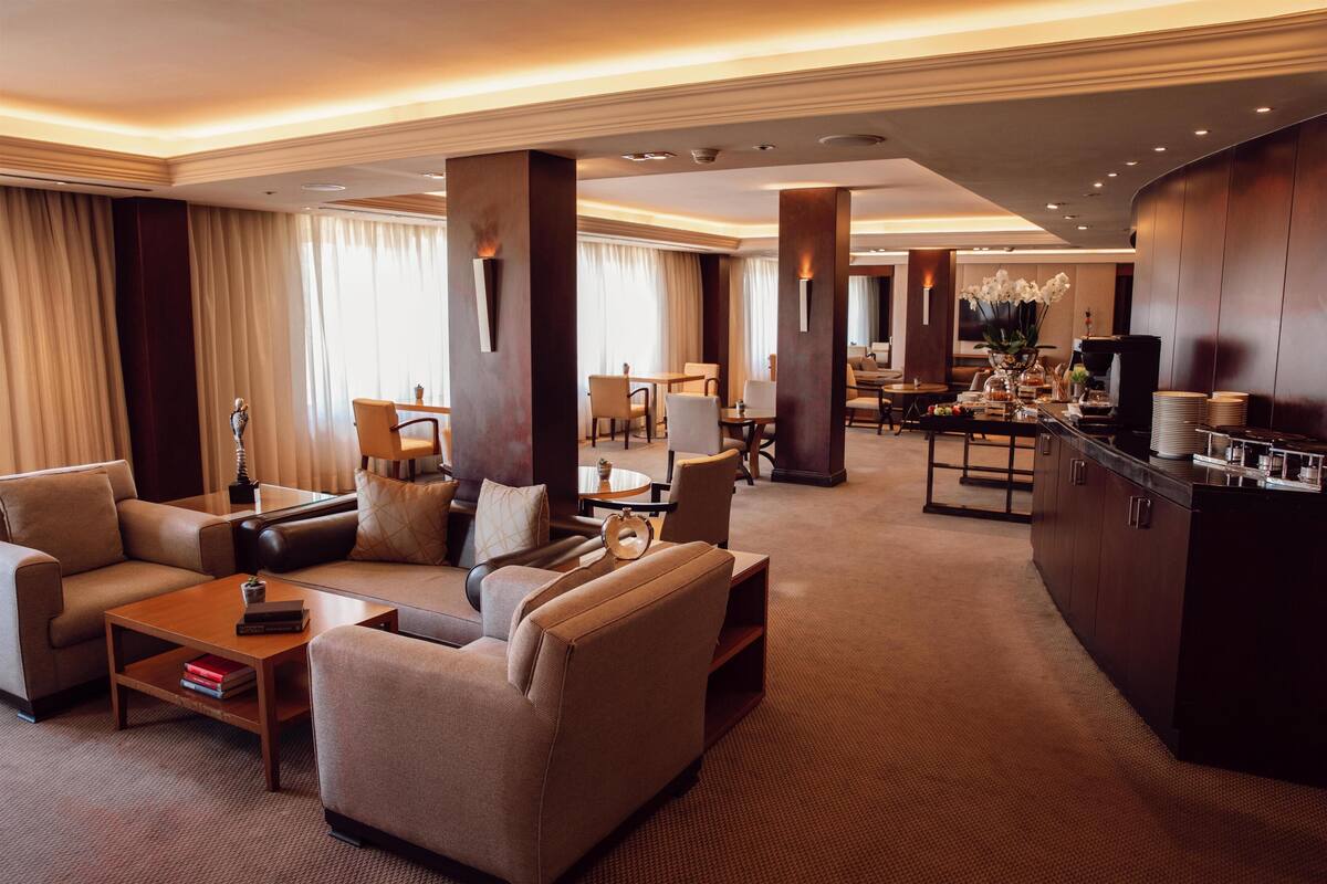 A spacious hotel lobby with a seating area, a bar, and a dining area.