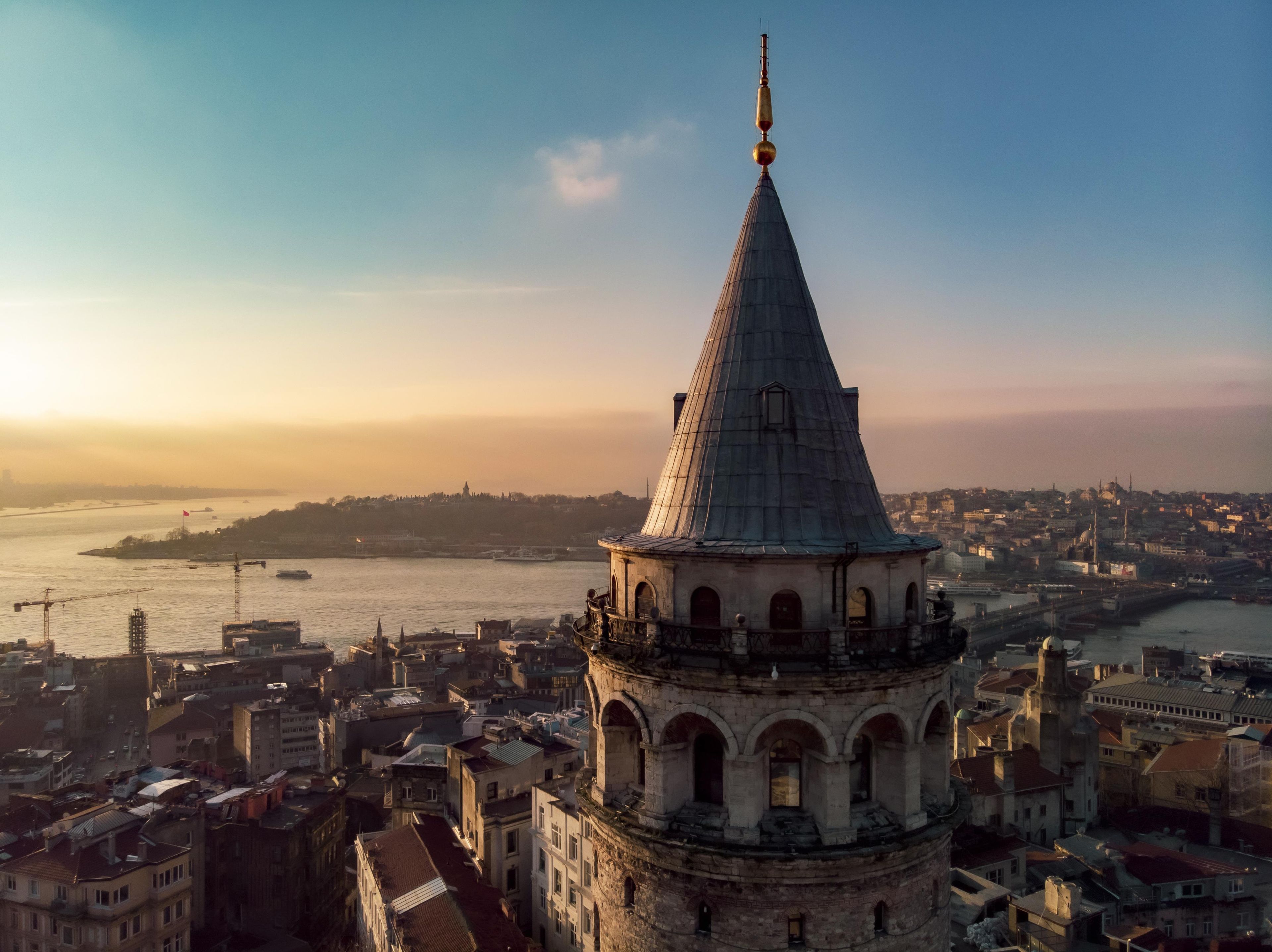 A historic building with a prominent tower, situated in a densely populated urban area with a river in the background.