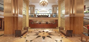 Recepció d'hotel amb taulell d'informació, dos sofàs, un penjallum i un paviment amb dibuixos.