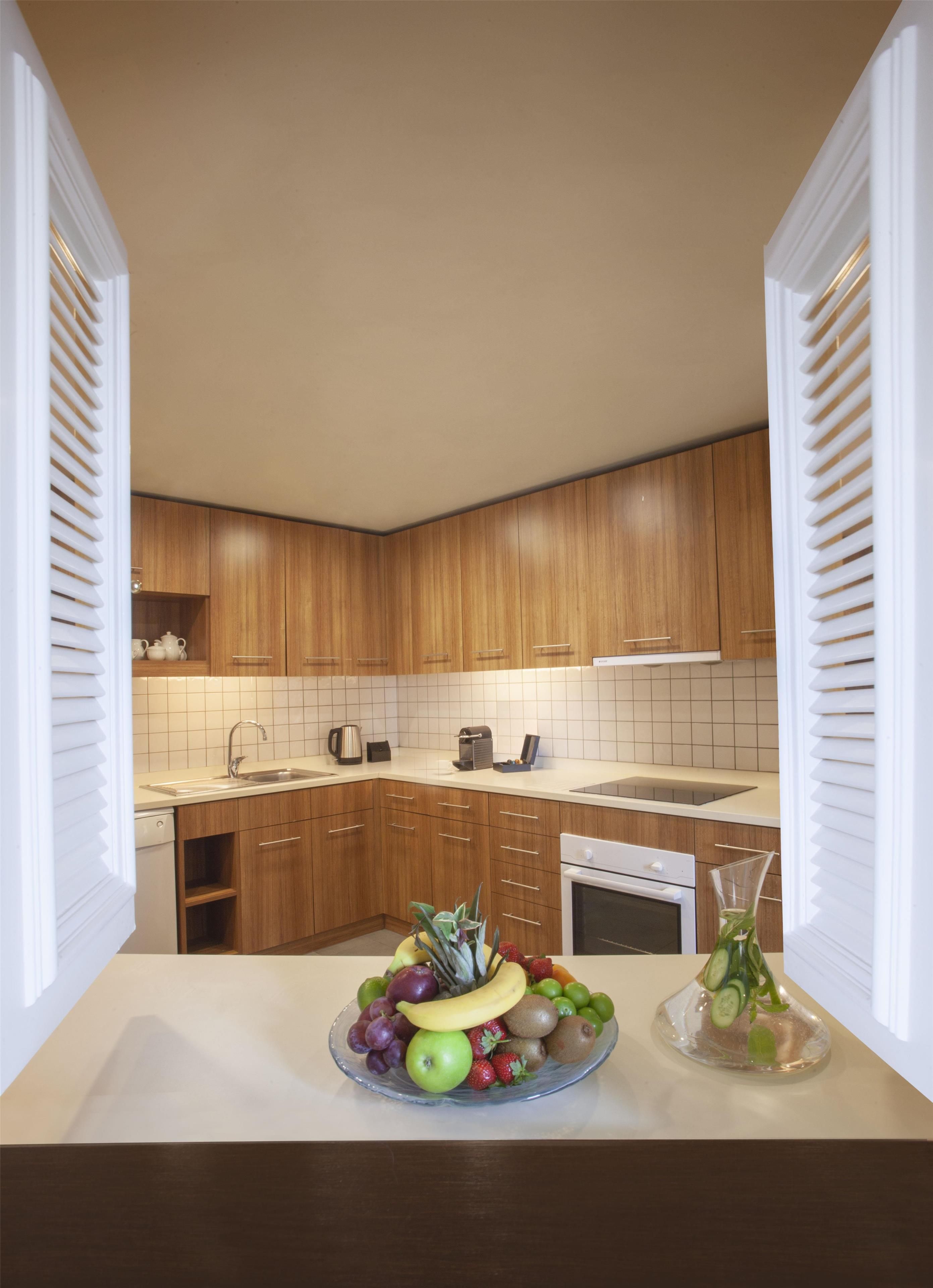 Una cocina moderna con armarios de madera, encimera blanca y un frutero sobre la encimera.