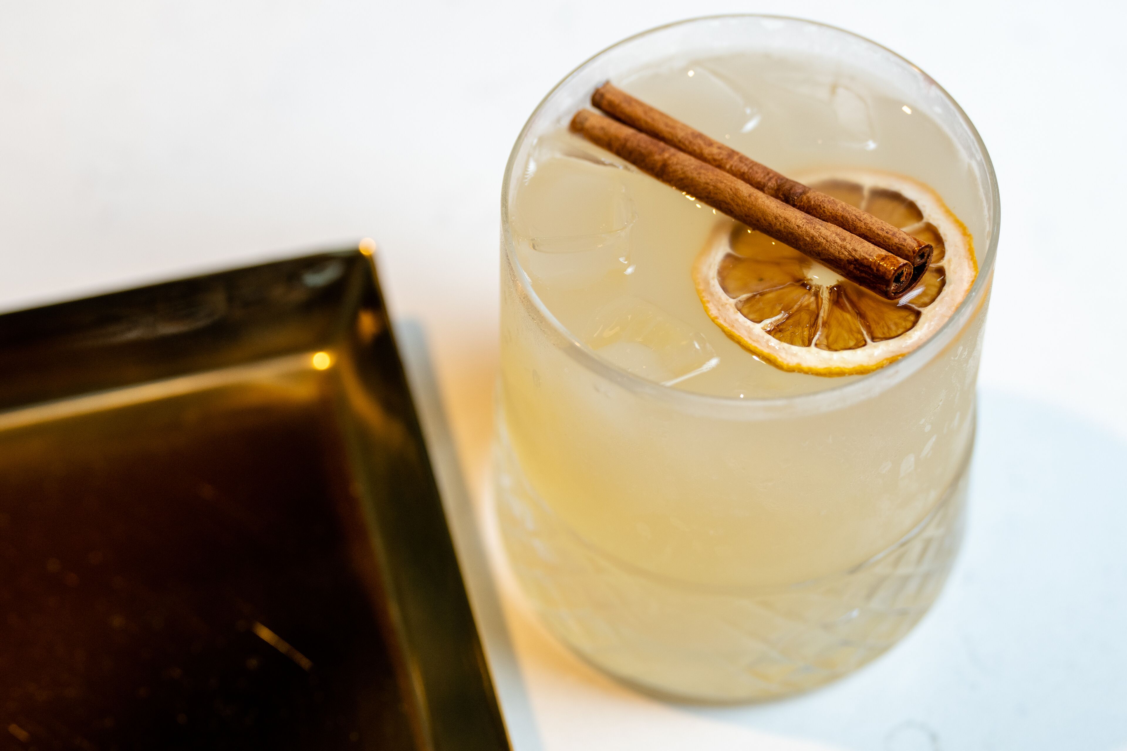 A clear glass with a cinnamon stick and a slice of lemon.