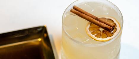 A clear glass with a cinnamon stick and a slice of lemon.