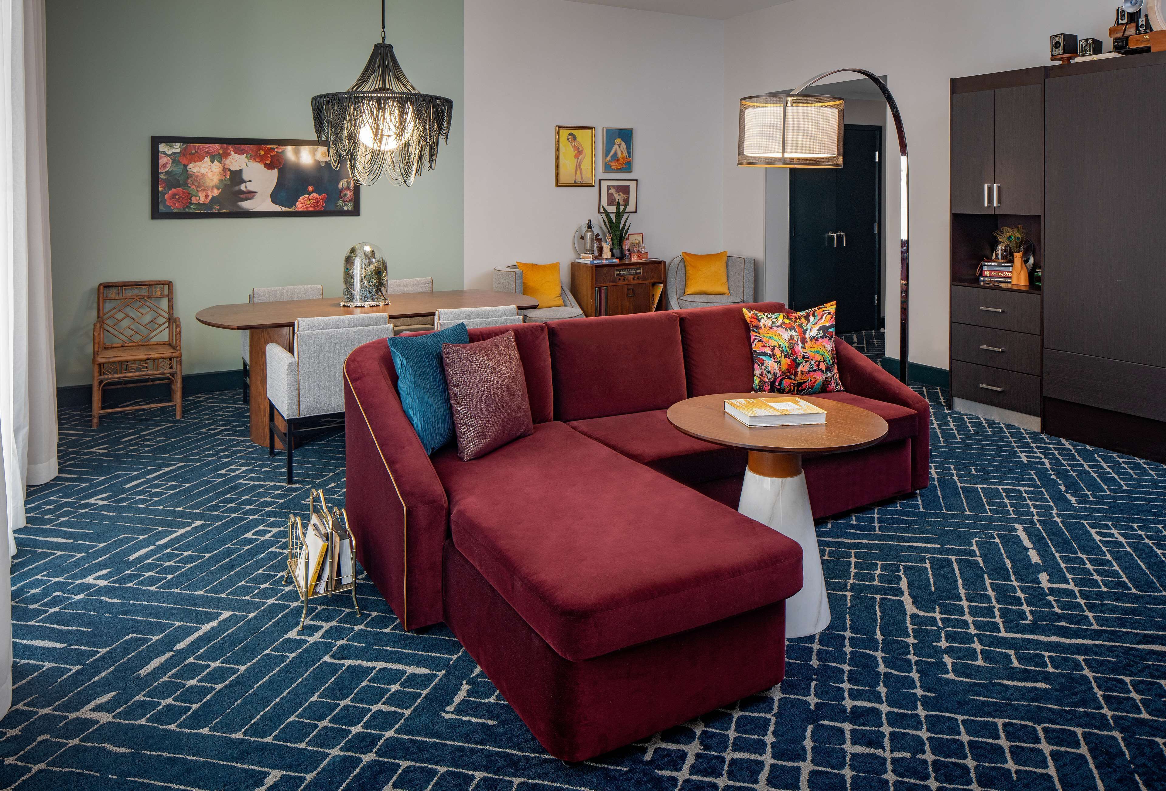 A modern living room with a sectional sofa, a dining table, and a large cabinet.