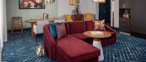 A modern living room with a sectional sofa, a dining table, and a large cabinet.