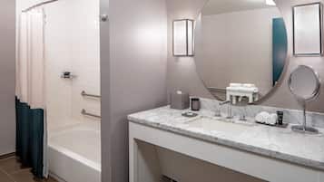 A modern bathroom with a bathtub, a large mirror, and a marble countertop.