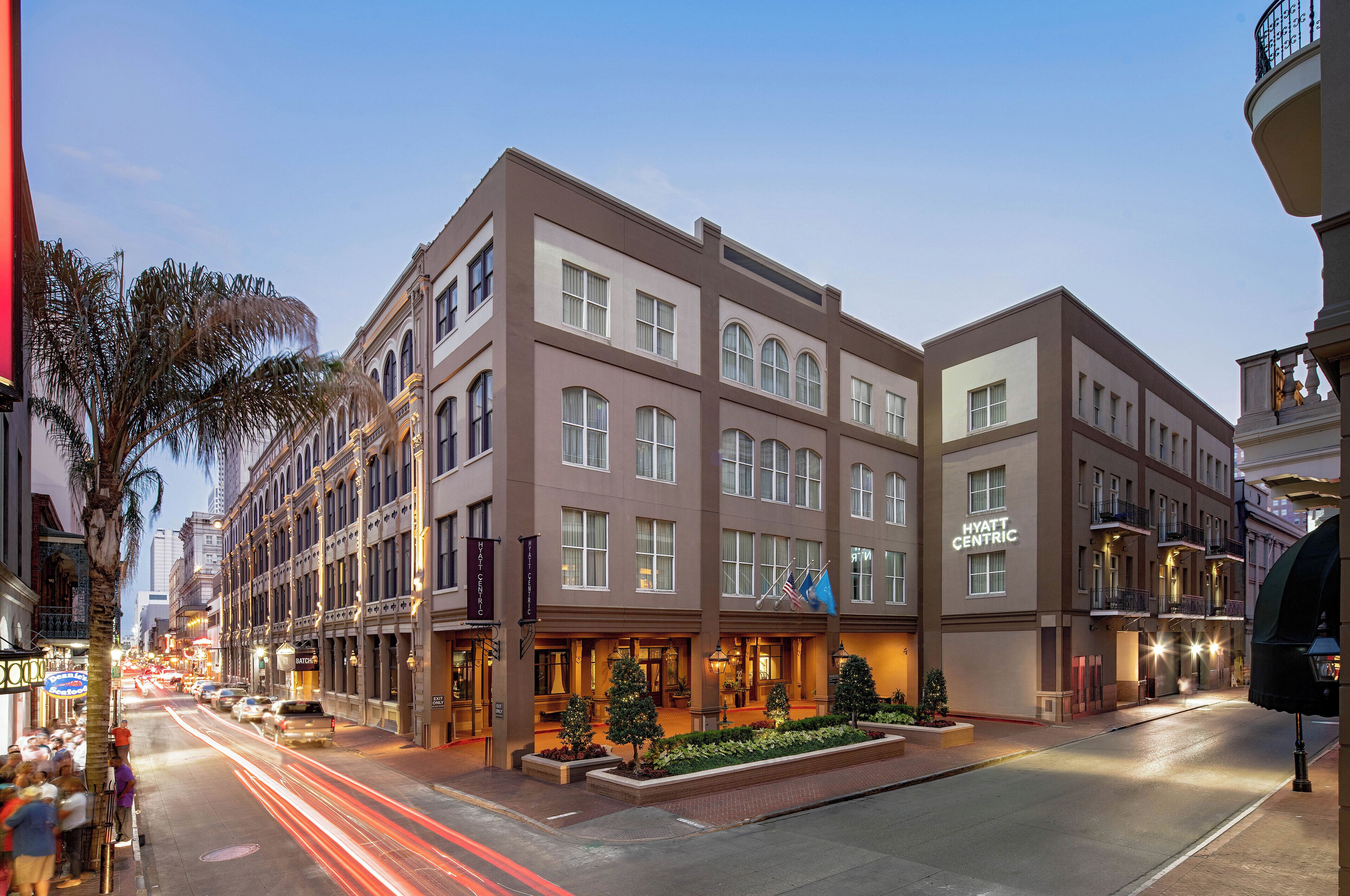 A multi-story hotel with a classic architectural design, featuring a central courtyard with plants and a seating area.