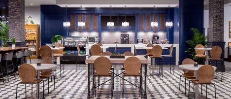 A modern restaurant with a checkered floor, bar seating, and a central counter with a coffee machine.
