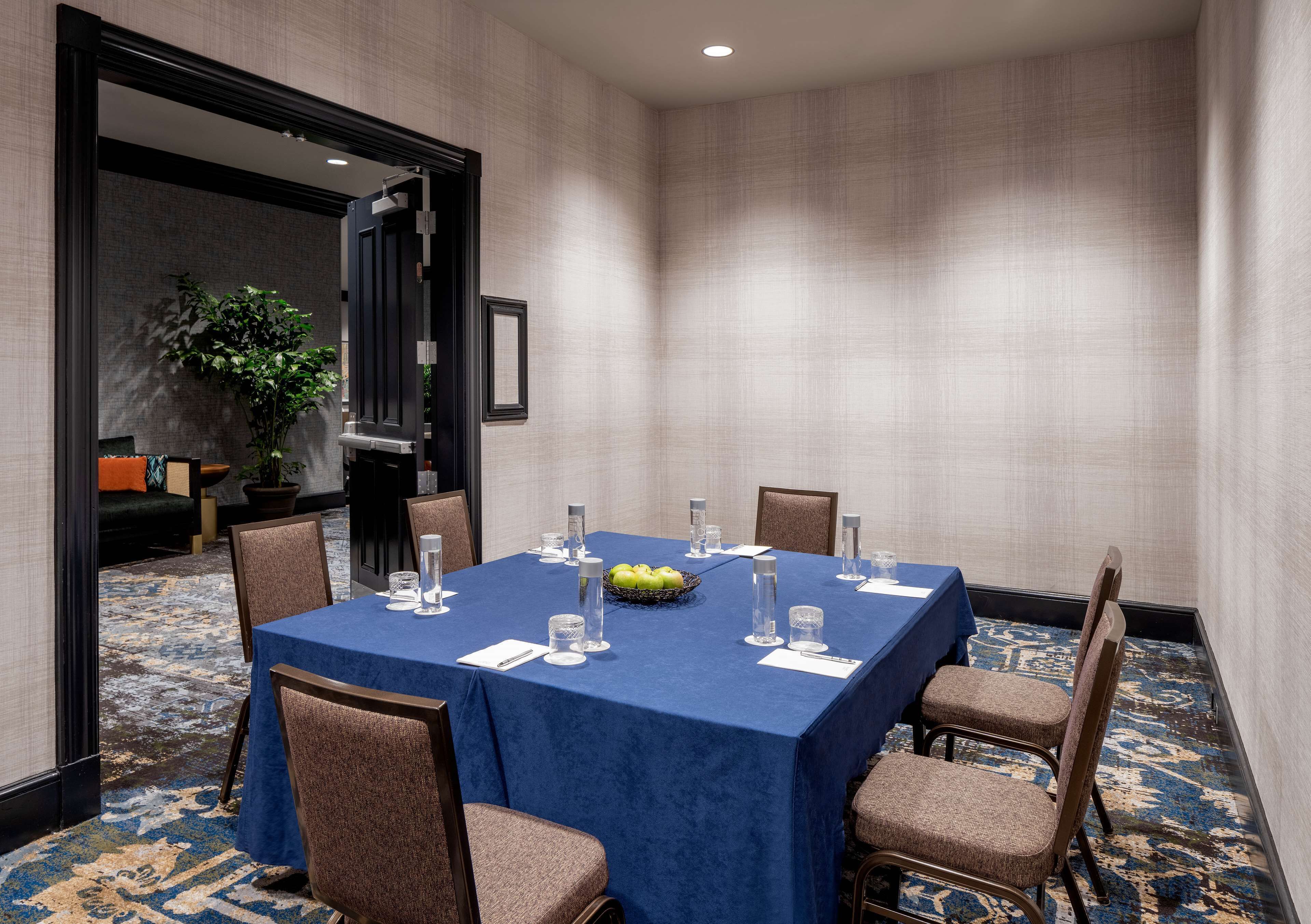 A conference room with a blue tablecloth, arranged chairs, and a fruit bowl.