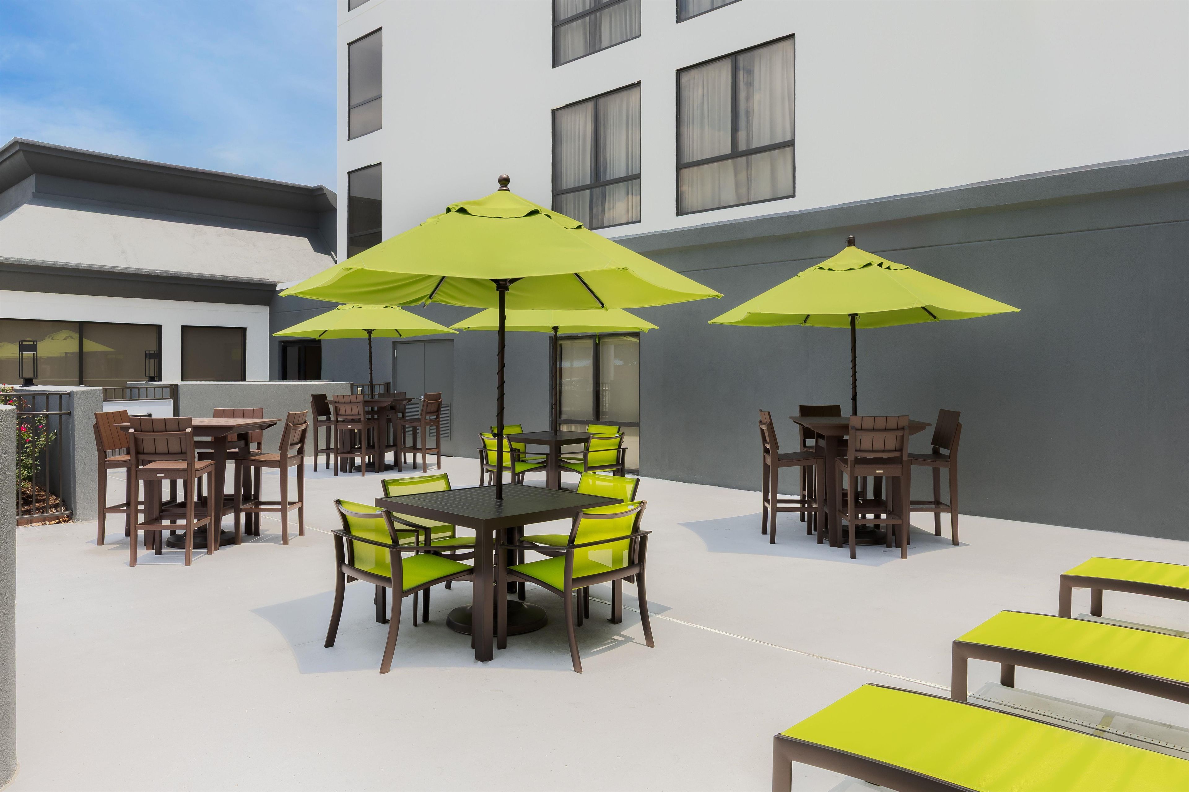 Un espace extérieur aménagé en terrasse, avec plusieurs tables et chaises, dont certaines sont dotées de parasols.
