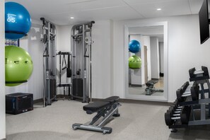Une salle de sport équipée de matériel d’exercice, notamment un banc, des poids et des ballons d’exercice.