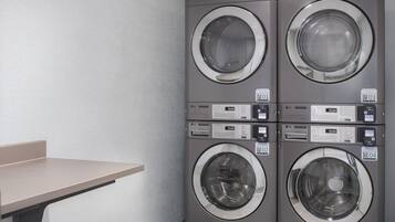 A four-washer laundry facility with direct drive controls and QR codes for payment.