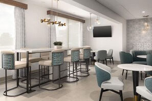 Un espace bar moderne avec des tabourets de bar, un téléviseur et un mur décoré de motifs.