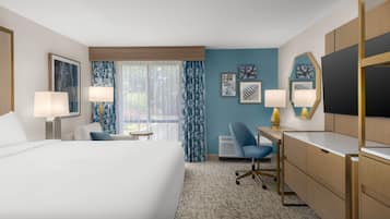 A hotel room with a bed, desk, chair, and a TV.